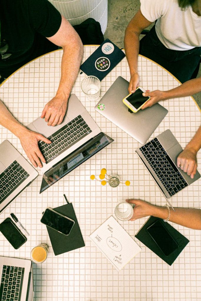 pexels-photo-3194519 Top view of a team collaborating with laptops, phones, and notes in a modern office.